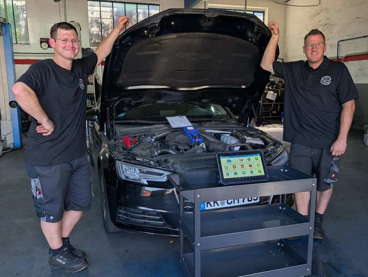 Christian Mooren und David Hunt bei der Inspektion eines Autos mit geöffneter Motorhaube und Diagnosegerät in der Werkstatt Niederkrüchten